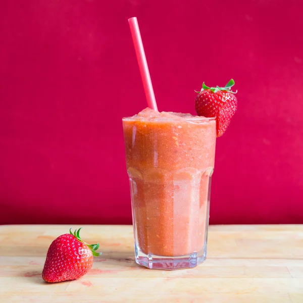 Strawberry smoothie in glass with straw