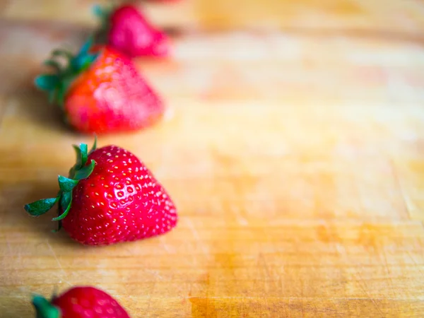 Rij van aardbeien op een houten bord met lege ruimte — Stockfoto