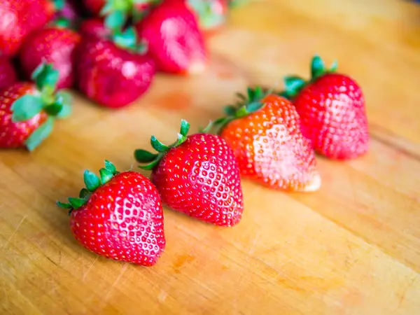 Rij van aardbeien op een houten bord — Stockfoto