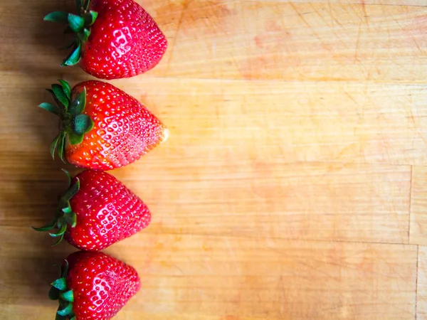 Rij van aardbeien op een houten bord met lege ruimte — Stockfoto