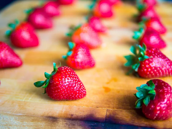 Rijen van aardbeien op een houten bord — Stockfoto