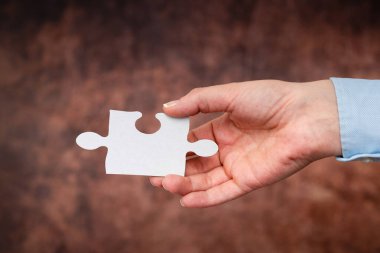 Yapboz 'un iki parçasını tutan eller iş yerinde kayıp fikirleri bulmak ve çözmek için işbirliği yapıyor. İşadamı çözüm için strateji buluyor, düşünceleri birbirine bağlıyor.