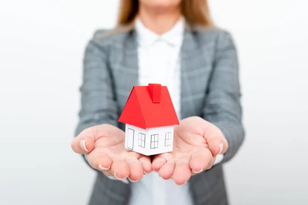 A Lady Holding Home In Business Outfit Presenting Possibility Of Owning Your Own Real Estate. Buying House Or Moving New Insurance Or Mortage Concept Shown By The Young Businesswoman. — 스톡 사진