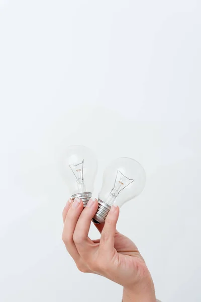 Mani della donna che tengono la lampada che presenta le idee per il progetto, l'uomo che mostra le lampadine e le nuove tecnologie, due lampadine tenute esibendo un altro parere — Foto Stock