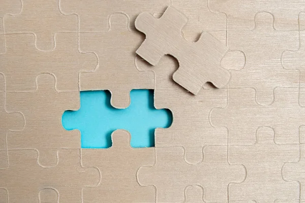 Yakın çekim beyaz testere desenli yapboz parçaları, kayıp parçalarla ilişkilendirilecek. Düz bir zeminde farklı doku ve kağıt aksesuarları ile yerleştirilmiş.