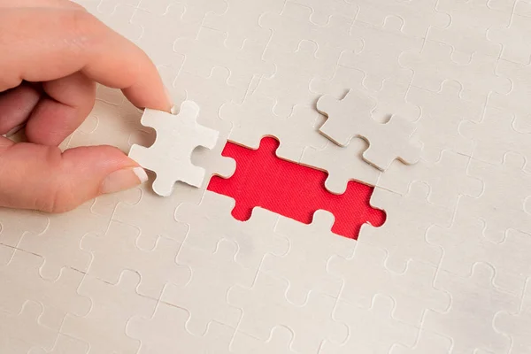 Close-Up White Jigsaw Pattern Puzzle Piezas que se conectarán con faltante última pieza colocada en un fondo plano con diferentes accesorios de textura y papel — Foto de Stock