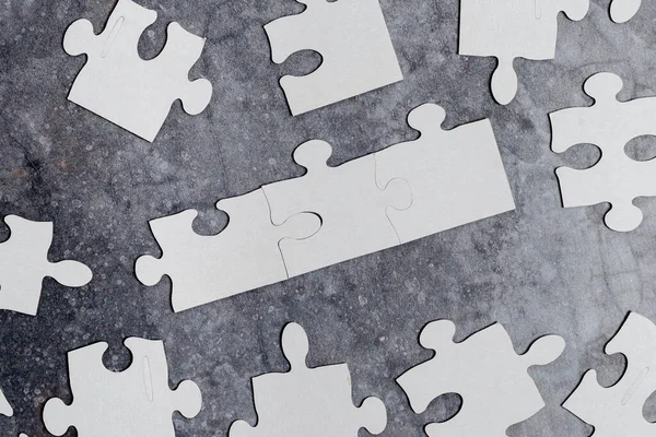 Close-up wit decoupeerzaagpatroon Puzzelstukjes te verbinden met ontbrekende laatste stuk geplaatst op een platte achtergrond met verschillende textuur en papier Supplies Accesories — Stockfoto