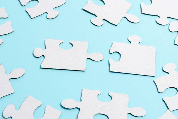 Close-Up White Jigsaw Pattern Puzzle Pieces To Be Connected With Missing Last Piece Positioned On A Flat Lay Background With Different Texture And Paper Supplies Accesories