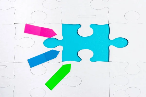 Close-Up White Jigsaw Pattern Puzzle Pieces To Be Connected With Missing Last Piece Positioned On A Flat Lay Background With Different Texture And Paper Supplies Accesories — Stock Photo, Image