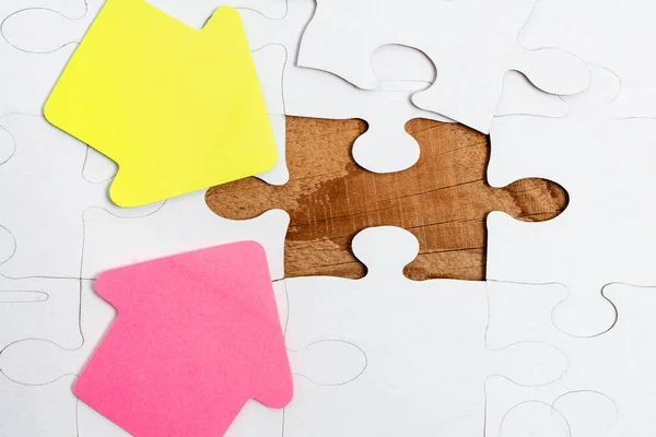 Close-Up White Jigsaw Pattern Puzzle Pieces To Be Connected With Missing Last Piece Positioned On A Flat Lay Background With Different Texture And Paper Supplies Accesories — Stock Photo, Image