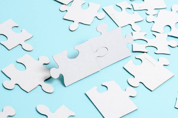 Close-Up White Jigsaw Pattern Puzzle Pieces To Be Connected With Missing Last Piece Positioned On A Flat Lay Background With Different Texture And Paper Supplies Accesories