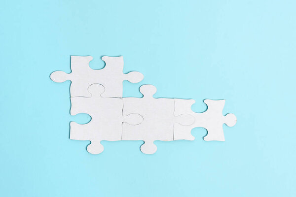 Close-Up White Jigsaw Pattern Puzzle Pieces To Be Connected With Missing Last Piece Positioned On A Flat Lay Background With Different Texture And Paper Supplies Accesories