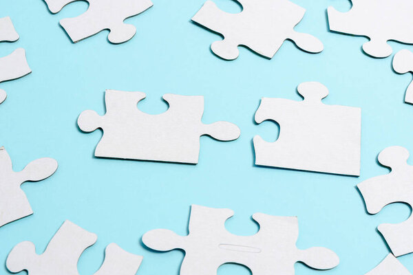 Close-Up White Jigsaw Pattern Puzzle Pieces To Be Connected With Missing Last Piece Positioned On A Flat Lay Background With Different Texture And Paper Supplies Accesories