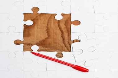 Yakın çekim beyaz testere desenli yapboz parçaları, kayıp parçalarla ilişkilendirilecek. Düz bir zeminde farklı doku ve kağıt aksesuarları ile yerleştirilmiş.