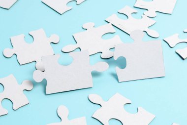 Yakın çekim beyaz testere desenli yapboz parçaları, kayıp parçalarla ilişkilendirilecek. Düz bir zeminde farklı doku ve kağıt aksesuarları ile yerleştirilmiş.