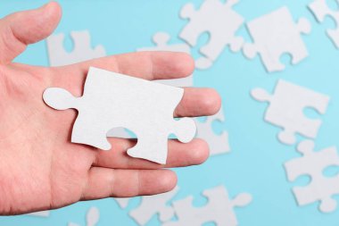 Yakın çekim beyaz testere desenli yapboz parçaları, kayıp parçalarla ilişkilendirilecek. Düz bir zeminde farklı doku ve kağıt aksesuarları ile yerleştirilmiş.