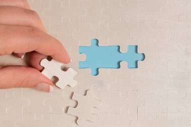 Yakın çekim beyaz testere desenli yapboz parçaları, kayıp parçalarla ilişkilendirilecek. Düz bir zeminde farklı doku ve kağıt aksesuarları ile yerleştirilmiş.
