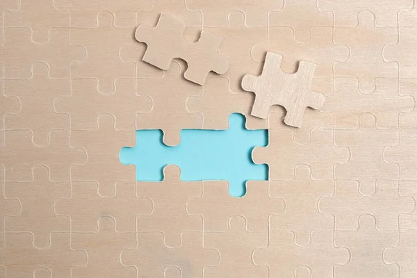 Close-Up White Jigsaw Pattern Puzzle Pieces To Be Connected With Missing Last Piece Positioned On A Flat Lay Background With Different Texture And Paper Supplies Accesories — Stock Photo, Image