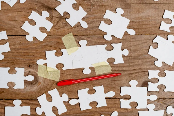 Yakın çekim beyaz testere desenli yapboz parçaları, kayıp parçalarla ilişkilendirilecek. Düz bir zeminde farklı doku ve kağıt aksesuarları ile yerleştirilmiş.