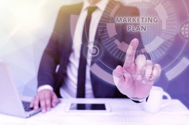 Metin başlığı Pazarlama Planını sunar. İşadamı Oturan Dizüstü bilgisayar ve Geleceği Gösteren Telefon Teknolojisini uygulayacakları genel iş stratejisi oluşturuldu..