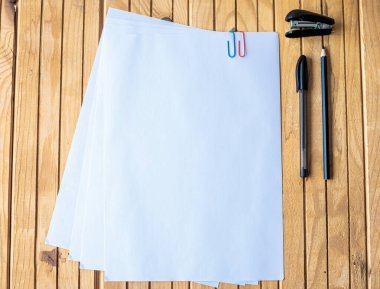 Boş kağıt, kalem ve zımbayla bir masanın üzerine çivilenmiş. Tahta bir masanın üzerine yerleştirilmiş, içi boş, içi boş kağıtlar sayfası..