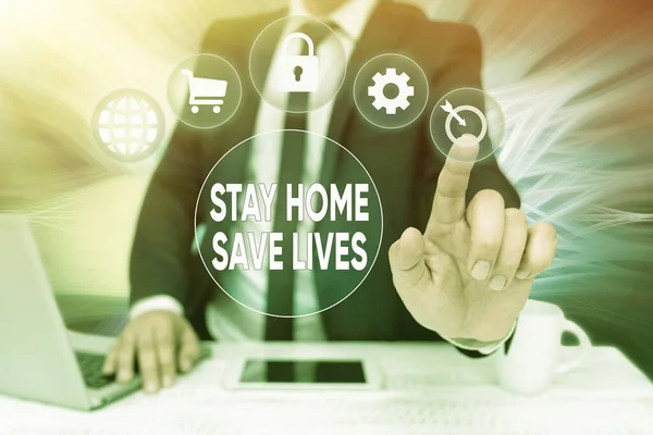 Text caption presenting Stay Home Save Lives. Word Written on lessen the number of infected patients by not leaving the house Bussiness Man Sitting Desk Laptop And Phone Pointing Futuristic Technology