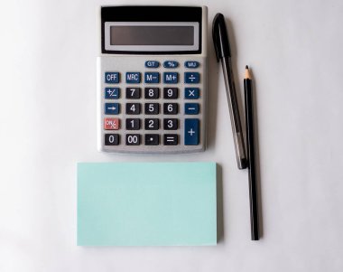 Boş bir Spiral Defter, hesap makinesi ve masanın üzerine yerleştirilmiş bir kalemle açıldı. Boş Çizgili Not Defteri ve Kalem Masanın üstünde Hesap Aygıtıyla.