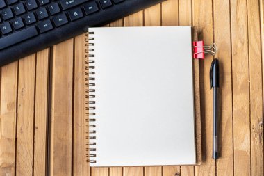 Ahşap masanın üstündeki klavye kaleminin yanında boş kırpılmış günlük. Masanın üzerine yerleştirilmiş Klip ve Kalem Klavye ile Boş Notepad Aç.