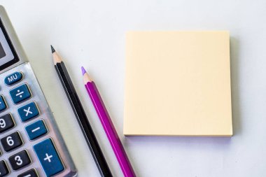 Düz Spiral Not Defteri. Hesap makinesinin yanında kalem ve masanın üstünde bozuk para var. Basit Not Defteri ve Ballpen Hesap Makinesi Masanın Üzerine yerleştirilmiş.