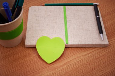 Masanın üstüne yerleştirilmiş kalemlerin içinde olduğu boş boş defterler. Tamam mı? Masadaki Renkli Balo Kalemleri Holü 'nün yanında Basit Boş Çizgili Notlar.