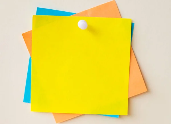 Notas de papel coloridas apiladas juntas y fijadas en la pared. Diferentes hojas de color de la nota adjunta en un fondo de pantalla llano con un pasador. —  Fotos de Stock