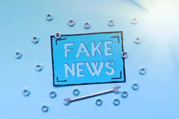 На табличці є напис Fake News. Бізнес-огляд Неправдива інформація публікується під виглядом автентичного новинного забезпечення інструментів і обладнання Механіка і інженера ремонту — стокове фото