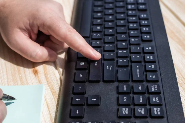 Mãos pressionando teclas de teclado do computador enquanto escreve com lápis no bloco de notas. Palmas digitando teclado Notebook e lápis de escrita sobre papel. — Fotografia de Stock