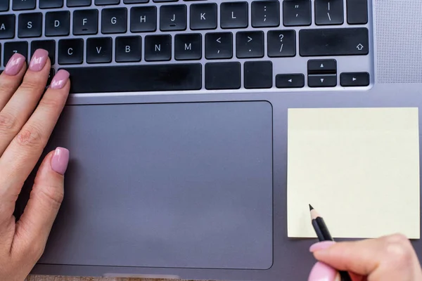 Mani premendo i tasti della tastiera del computer durante la scrittura con matita nel blocco note. Palme Dattilografia Blocco note Tastiera e scrittura matita su carta. — Foto Stock