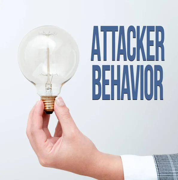 Handwriting text Attacker Behavior. Word Written on analyze and predict the attacker behavior of the attack Hand holding lamp showing or presenting new technology ideas