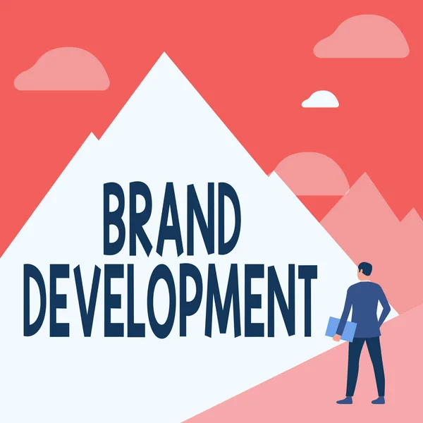 Textskylt som visar Brand Development. Affärsidé att förbättra kundernas kunskap och åsikter om ett varumärke Gentleman In Suit Standing Holding Notebook Facing Tall Mountain Range. — Stockfoto