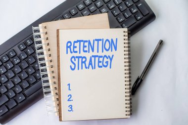 Sign displaying Retention Strategy. Business idea activities to reduce employee turnover and attrition Two Plain Lined Spiral Notebooks With Pen And Keyboard On Table.