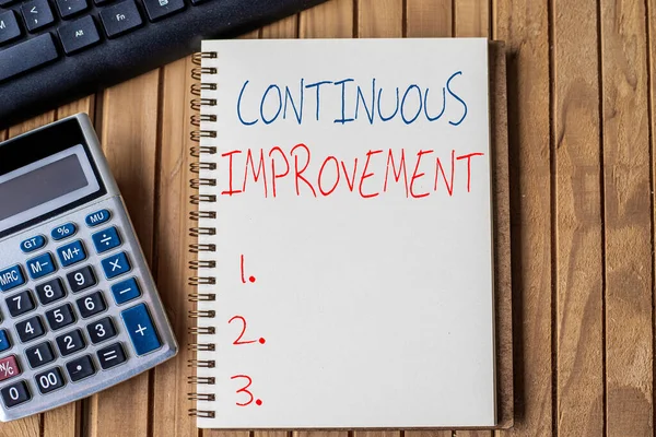 Text caption presenting Continuous Improvement. Business showcase making small consistent improvements over time Blank Open Spiral Notebook With Calculator Keyboard Pen Placed Over Table.