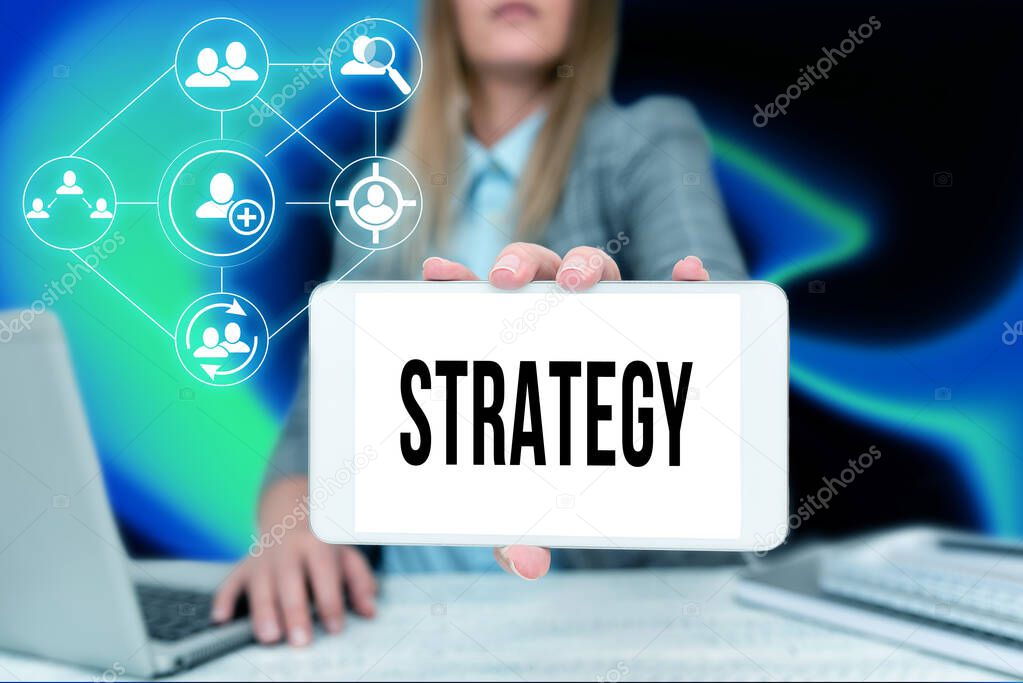 Handwriting text Strategy. Business showcase action plan or strategy designed to achieve an overall goal Business Woman Sitting In Office Holding Mobile Displaying Futuristic Ideas.