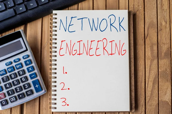 Writing displaying text Network Engineering. Business idea professional who has the skills to oversee the net Blank Open Spiral Notebook With Calculator Keyboard Pen Placed Over Table.