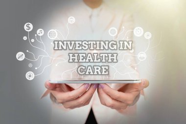 Sağlık Hizmetleri Yatırım el yazısı metni. İnternet Konsepti, fütüristik Teknolojiyi Gösteren Üniformalı Kadın Ayakta Durma ve Tutma Tabletinin Bakımı veya Geliştirilmesine para yatırdı.
