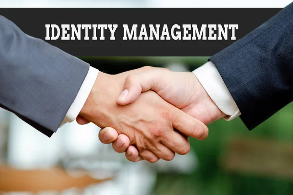 Writing displaying text Identity Management. Business showcase administration of individual identities within a system Two Professional Well-Dressed Corporate Businessmen Handshake Indoors