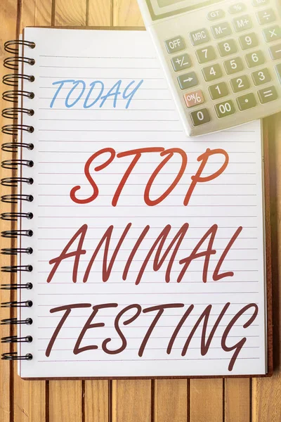 Концептуальная подпись Stop Animal Testing. Бизнес-подход положил конец экспериментам на животных или исследованиям Простой открытый спиральный ноутбук с калькулятором, размещенным на столе. — стоковое фото