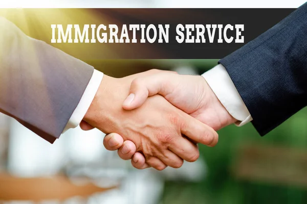 Text caption presenting Immigration Service. Business approach responsible for law regarding immigrants and immigration Two Professional Well-Dressed Corporate Businessmen Handshake Indoors