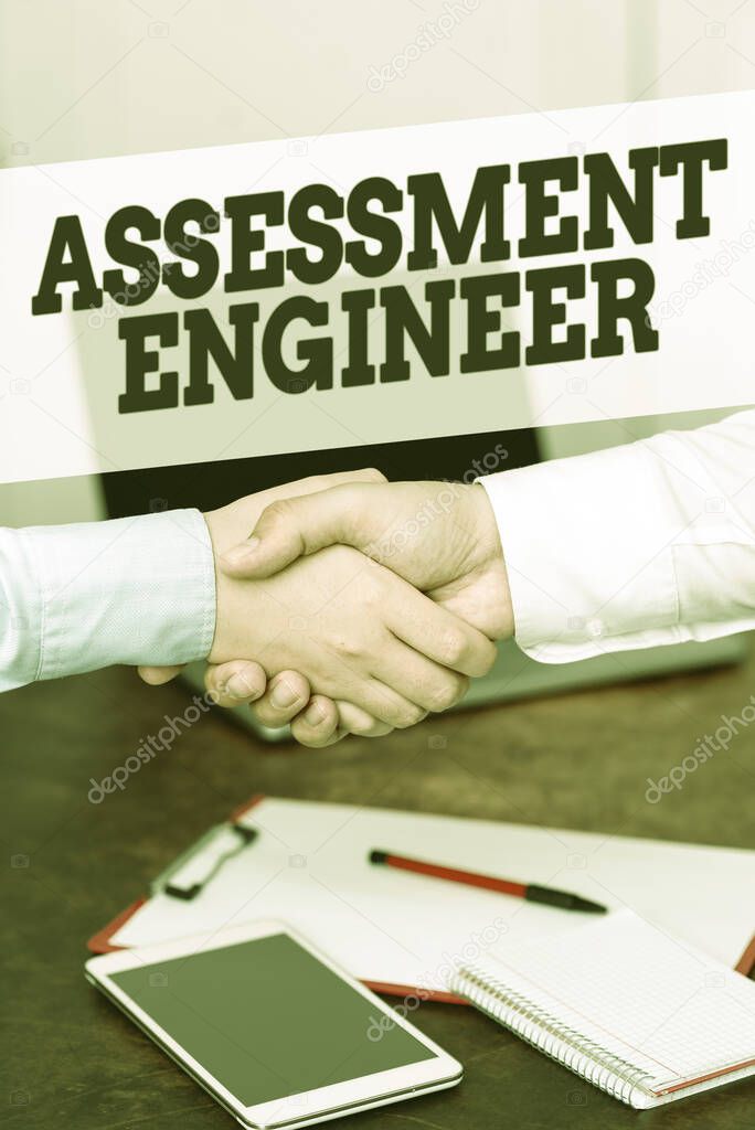 Hand writing sign Assessment Engineer. Internet Concept gives solutions to the complexities of developing tests Two Professional Well-Dressed Corporate Businessmen Handshake Indoors