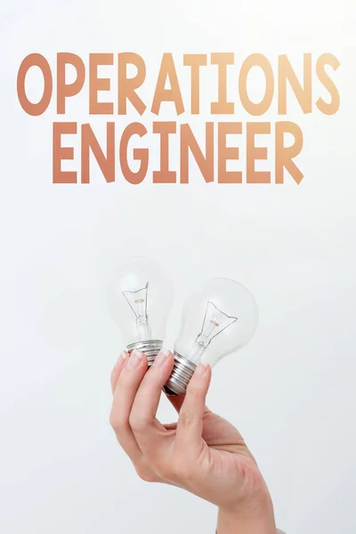 Handwriting text Operations Engineer. Business idea analyze and design operation that will improve work flow Hand holding two lamp showing or presenting new technology ideas