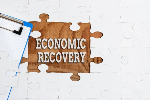 Text showing inspiration Economic Recovery. Business approach rise of business activity signaling the end of a recession Building An Unfinished White Jigsaw Pattern Puzzle With Missing Last Piece — стоковое фото