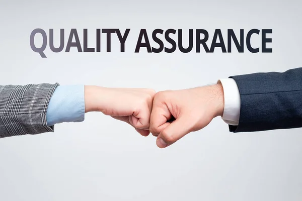 Sign displaying Quality Assurance. Concept meaning preventing mistakes and defects in manufactured products Two Professional Well-Dressed Corporate Businessmen Handshake Indoors