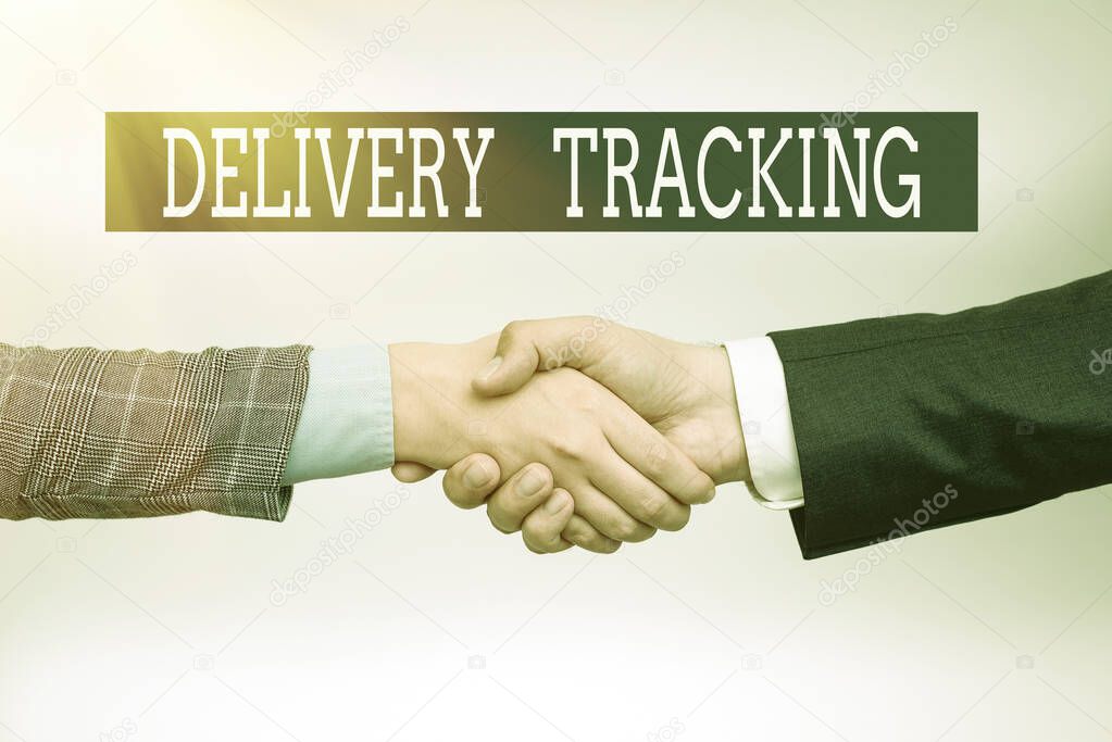 Hand writing sign Delivery Tracking. Word Written on the process of localizing shipping containers and mails Two Professional Well-Dressed Corporate Businessmen Handshake Indoors