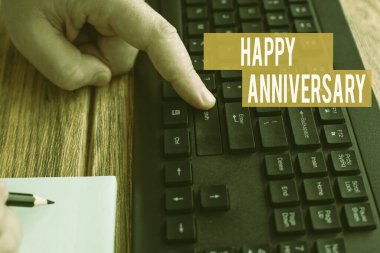 Mutlu Yıl dönümleri metni yazılıyor. Bu kavram, eski bir olayın yıllık yinelenen tarihi, Not Defterinde Kalemle Yazarken Eller Bilgisayarın Klavye Tuşlarına Basar.